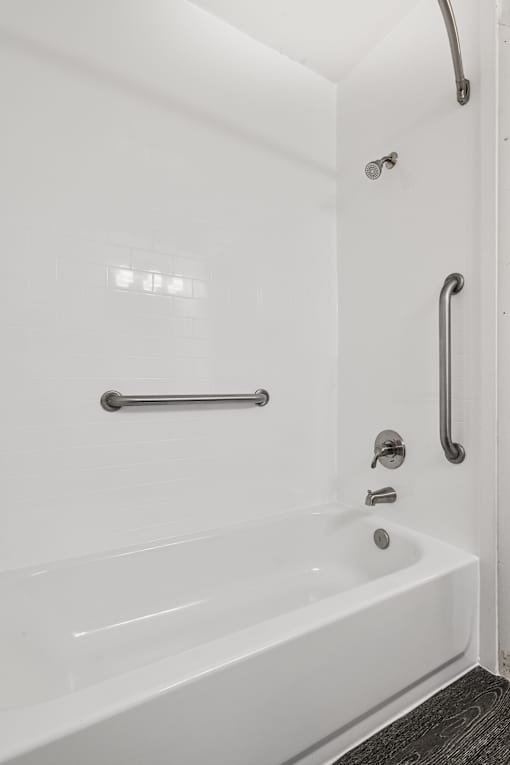 A white bathtub with a silver faucet and grab bar.